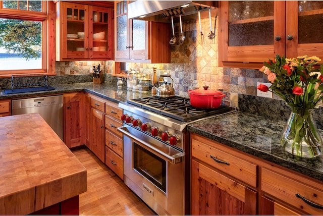 kitchen with tasteful backsplash, wooden counters, exhaust hood, and appliances with stainless steel finishes