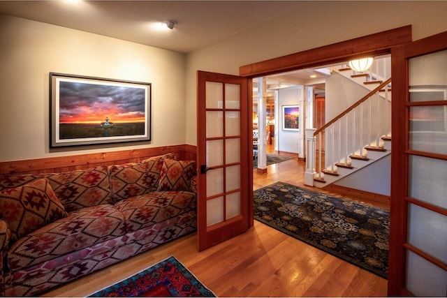 living room with wood finished floors, stairs, and french doors