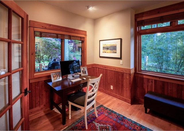 office space featuring wainscoting, wood walls, and light wood-type flooring