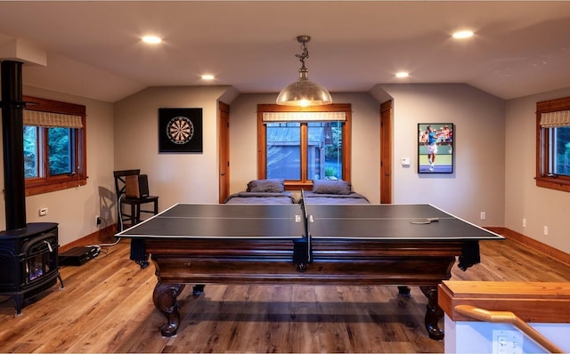 game room with lofted ceiling, wood finished floors, a wood stove, and baseboards