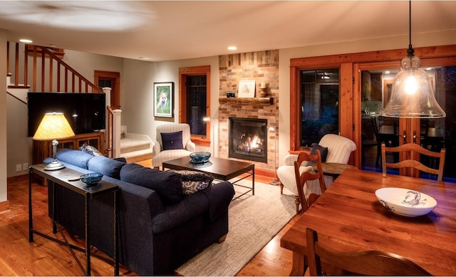 living area featuring baseboards, stairway, wood finished floors, and a fireplace
