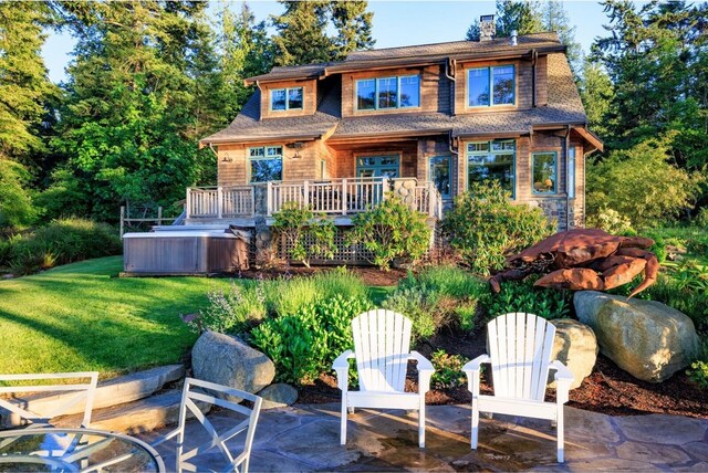 back of property featuring a chimney, a patio area, a deck, and a lawn