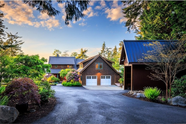 exterior space with a garage, aphalt driveway, and metal roof