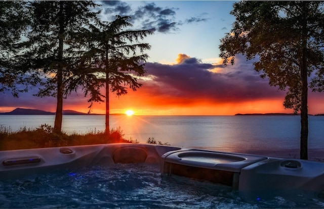 exterior space with a water view and a hot tub