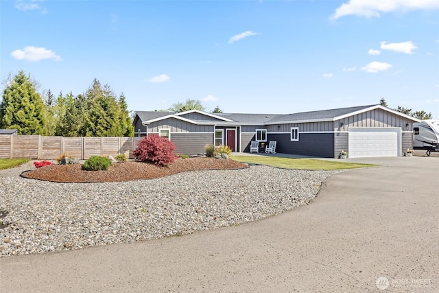 view of front of house with fence, board and batten siding, driveway, and a garage
