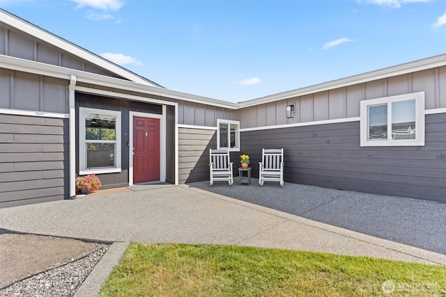 property entrance featuring board and batten siding and a patio area