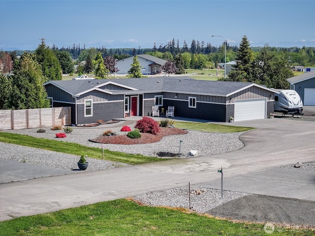 single story home featuring board and batten siding, fence, driveway, and a garage