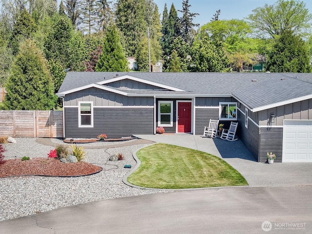 view of front of property with a shingled roof, fence, board and batten siding, and a front yard