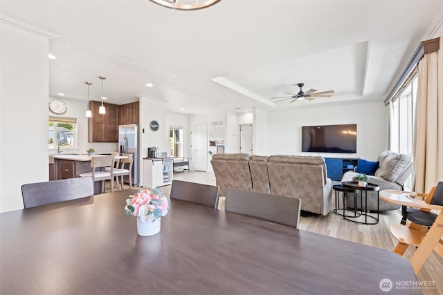 dining area with a raised ceiling, recessed lighting, ceiling fan, and light wood finished floors
