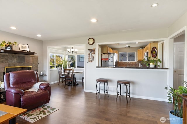 living area with recessed lighting, a notable chandelier, dark wood finished floors, and a tile fireplace