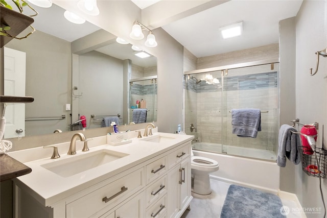 bathroom with a sink, combined bath / shower with glass door, toilet, and double vanity