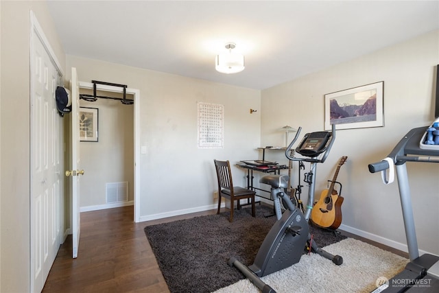 exercise area with baseboards, visible vents, and wood finished floors