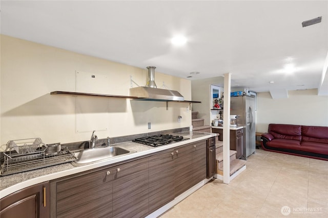 kitchen with light tile patterned flooring, wall chimney range hood, gas cooktop, light countertops, and a sink