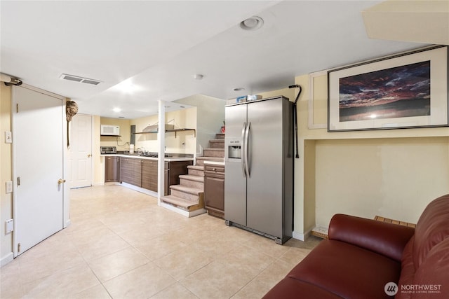 kitchen featuring visible vents, light countertops, light tile patterned floors, baseboards, and stainless steel fridge