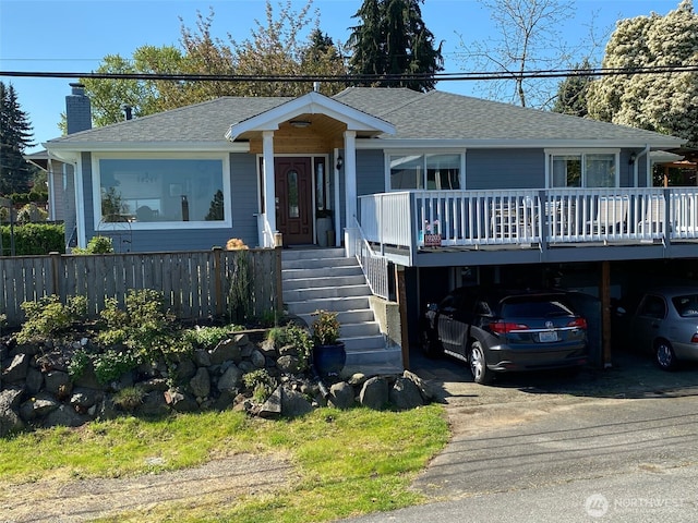 view of front of house with fence, a shingled roof, a deck, a chimney, and driveway