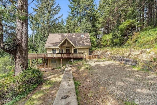 rustic home featuring a wooden deck and a forest view