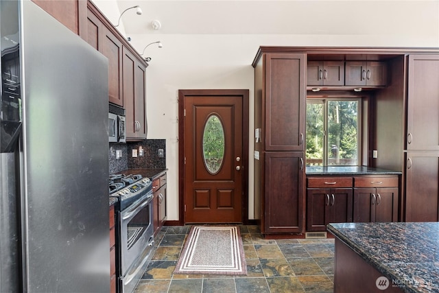 kitchen featuring stone finish floor, dark stone counters, stainless steel appliances, tasteful backsplash, and visible vents