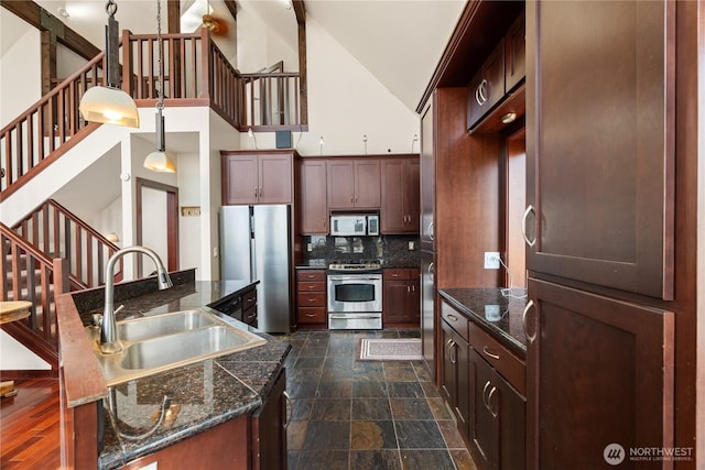 kitchen with stone finish floor, decorative backsplash, a sink, high vaulted ceiling, and stainless steel appliances