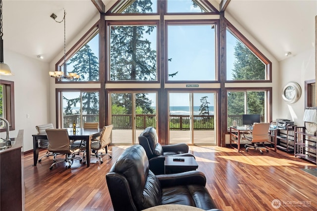 living area with a healthy amount of sunlight, high vaulted ceiling, and wood finished floors