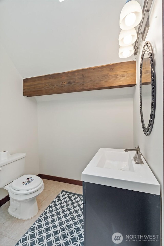 half bathroom featuring vanity, baseboards, tile patterned flooring, and toilet