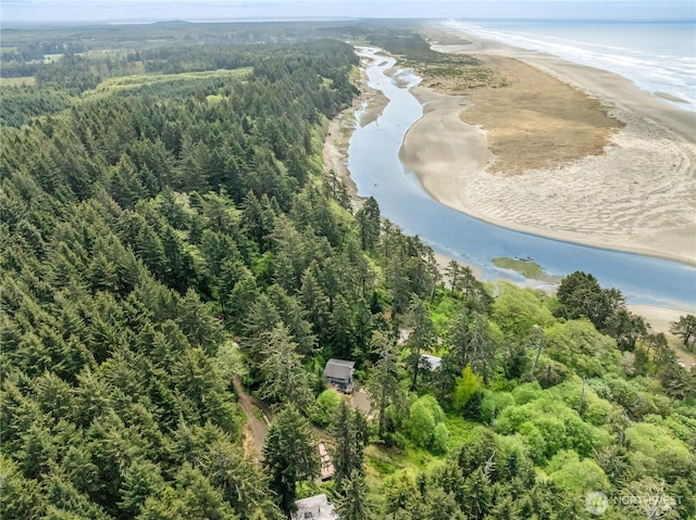 drone / aerial view featuring a beach view, a water view, and a view of trees