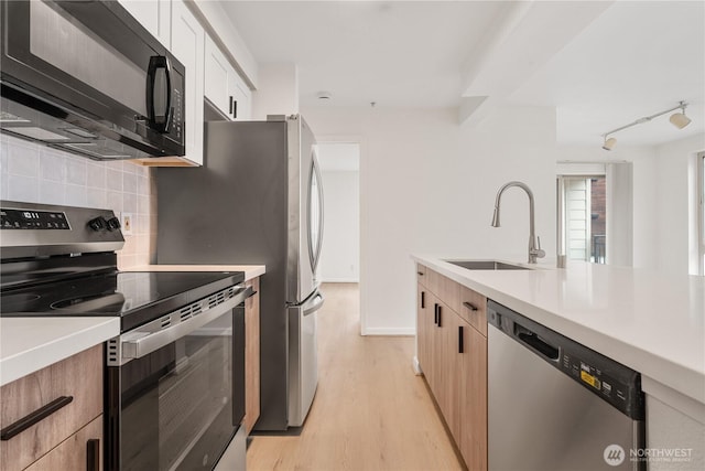 769 Hayes St Unit 405, Seattle, WA 98109 - kitchen with appliances with stainless steel finishes, tasteful backsplash, light countertops, and light wood finished floors