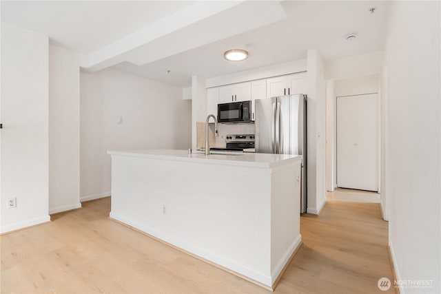 769 Hayes St Unit 405, Seattle, WA 98109 - kitchen featuring black microwave, light wood-style flooring, stainless steel electric range, white cabinetry, and an island with sink