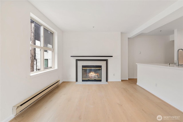 769 Hayes St Unit 405, Seattle, WA 98109 - unfurnished living room featuring a baseboard heating unit, light wood finished floors, and a tile fireplace