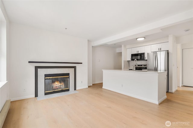 769 Hayes St Unit 405, Seattle, WA 98109 - unfurnished living room featuring light wood-style flooring and a tiled fireplace