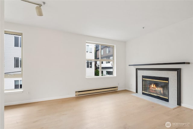 769 Hayes St Unit 405, Seattle, WA 98109 - unfurnished living room featuring a baseboard heating unit, wood finished floors, and a tile fireplace