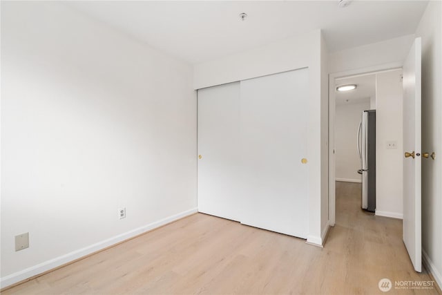 769 Hayes St Unit 405, Seattle, WA 98109 - unfurnished bedroom featuring freestanding refrigerator, light wood finished floors, and a closet
