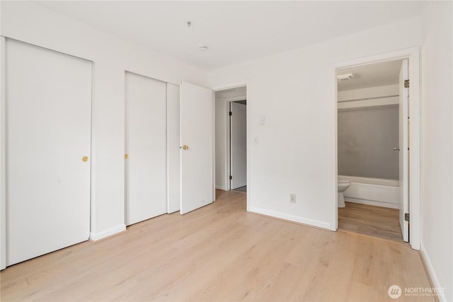 769 Hayes St Unit 405, Seattle, WA 98109 - unfurnished bedroom with light wood-style floors, two closets, and ensuite bathroom