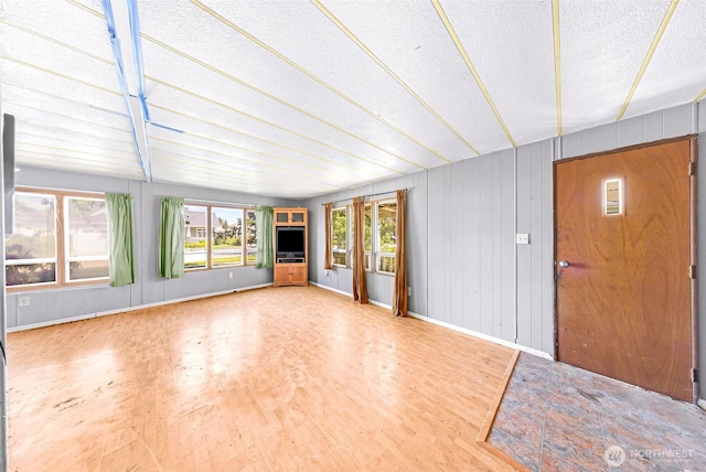 unfurnished living room with baseboards, a textured ceiling, and wood finished floors