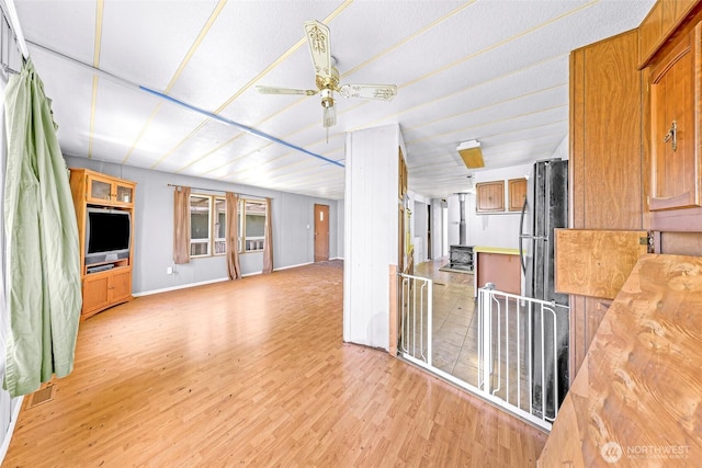 interior space featuring light wood-style floors, baseboards, and ceiling fan
