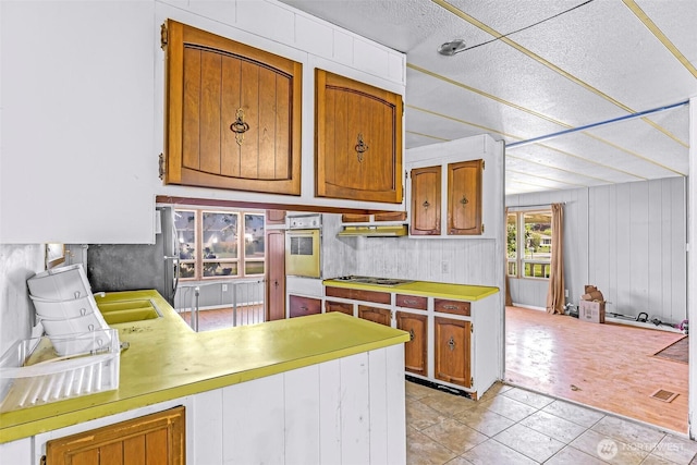 kitchen with electric stovetop, a textured ceiling, white oven, light tile patterned floors, and light countertops