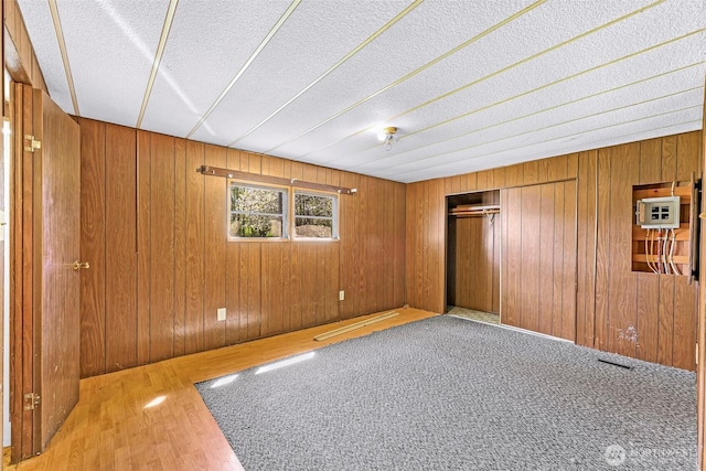 empty room with a textured ceiling, wood walls, and wood finished floors
