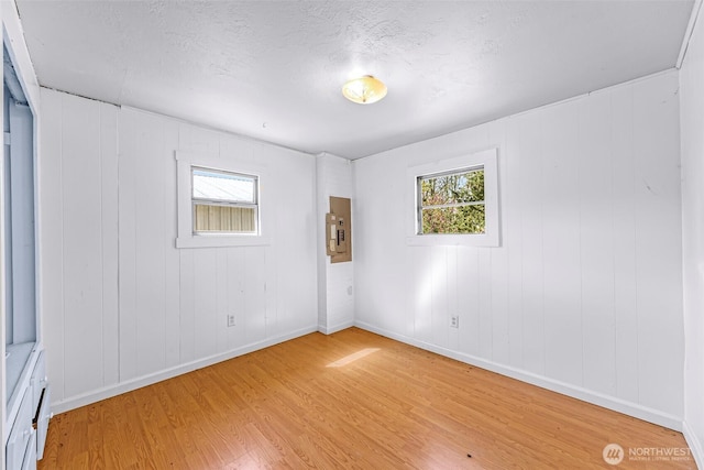 unfurnished room featuring baseboards, electric panel, and light wood-style flooring