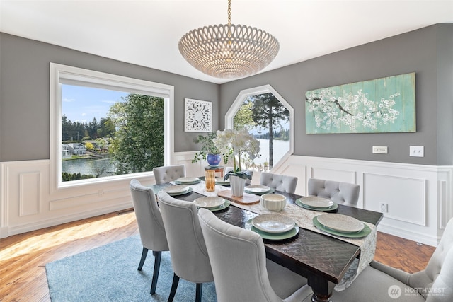 dining space with a decorative wall, an inviting chandelier, a healthy amount of sunlight, and a wainscoted wall