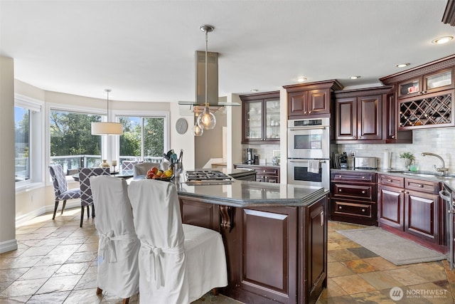 kitchen featuring a sink, appliances with stainless steel finishes, tasteful backsplash, and stone tile flooring