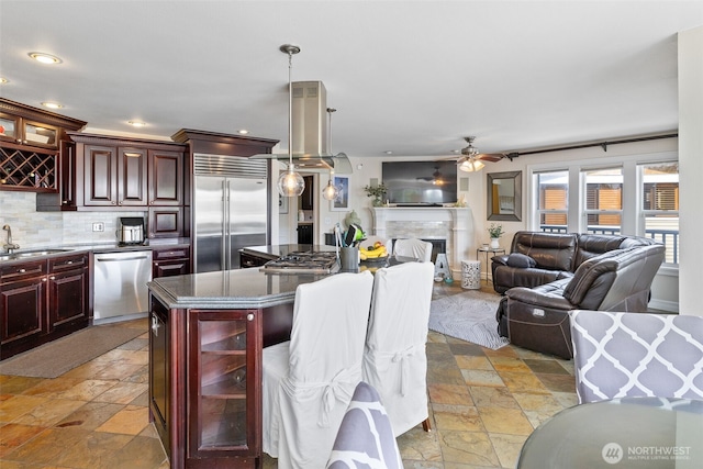 kitchen with dark brown cabinets, a ceiling fan, appliances with stainless steel finishes, and stone tile flooring