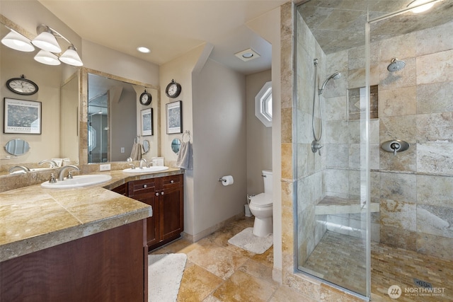 full bath with vanity, a tile shower, and toilet