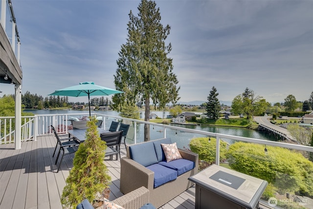 wooden terrace with outdoor dining space, a water view, and an outdoor living space