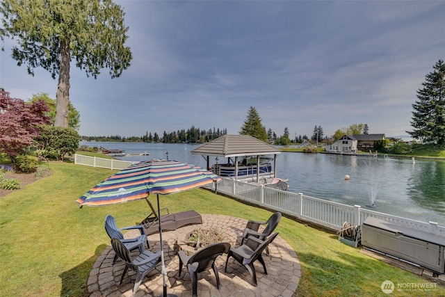 exterior space with a yard, a water view, fence, and a fire pit