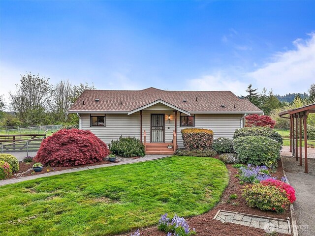 single story home with fence, a shingled roof, and a front yard