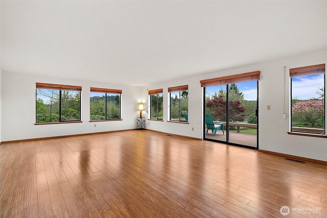 interior space with plenty of natural light, baseboards, wood finished floors, and visible vents