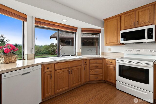 kitchen featuring a sink, light countertops, white appliances, and wood finished floors