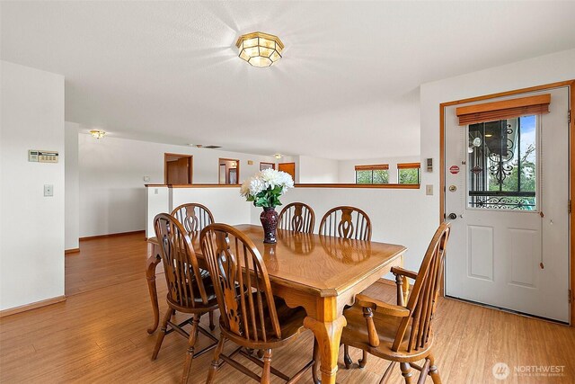 dining space with baseboards and light wood-style floors