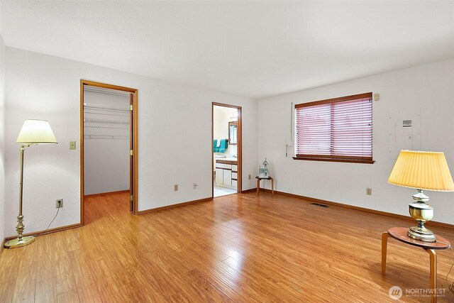 unfurnished room featuring visible vents, light wood finished floors, and baseboards