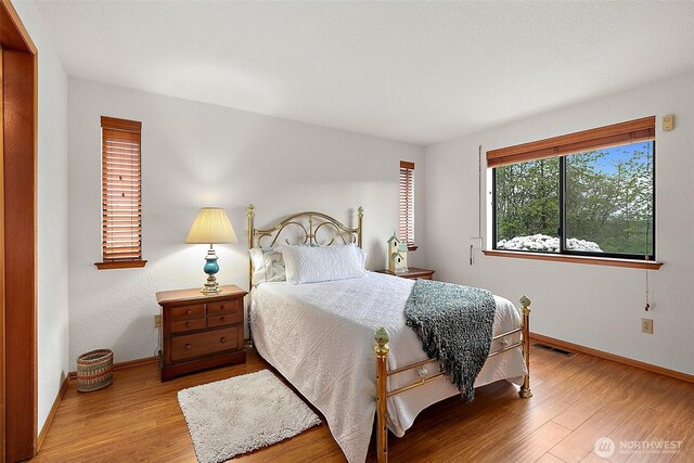 bedroom with visible vents, baseboards, and wood finished floors