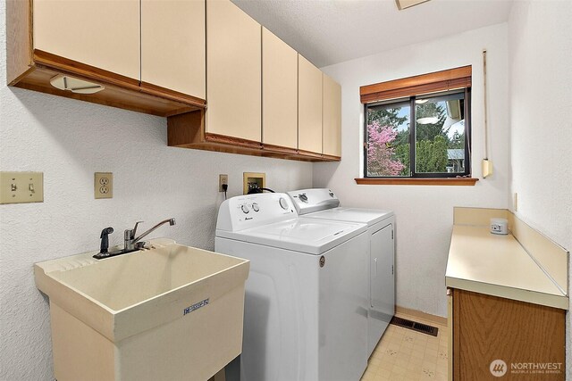 laundry room featuring baseboards, light floors, separate washer and dryer, a sink, and cabinet space